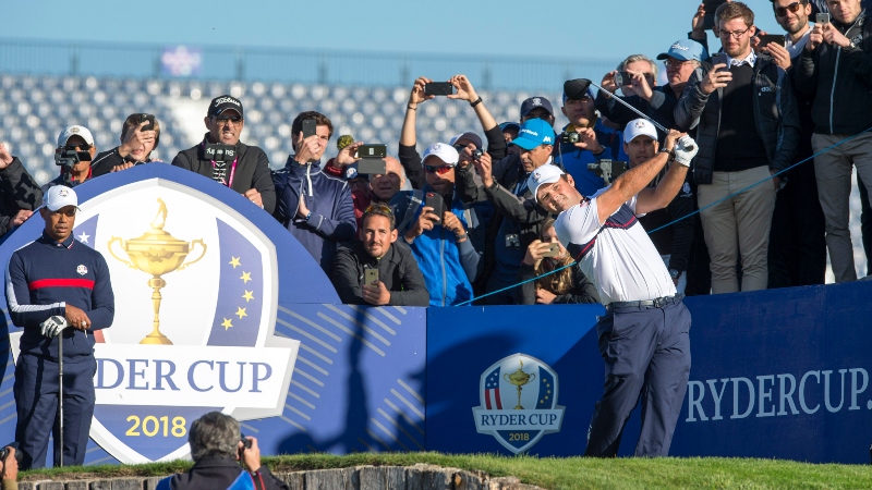 Patrick Reed tees off at the third as Tiger Woods looks on during a Ryder Cup practice round at Le Golf National.