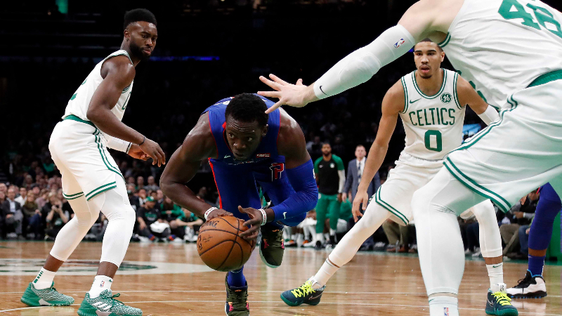Detroit Pistons center Andre Drummond (0) looks to pass off the ball as he falls to the floor between Boston Celtics forward Jayson Tatum (0), center Aron Baynes (46) and guard Jaylen Brown (7) during the first quarter at TD Garden.
