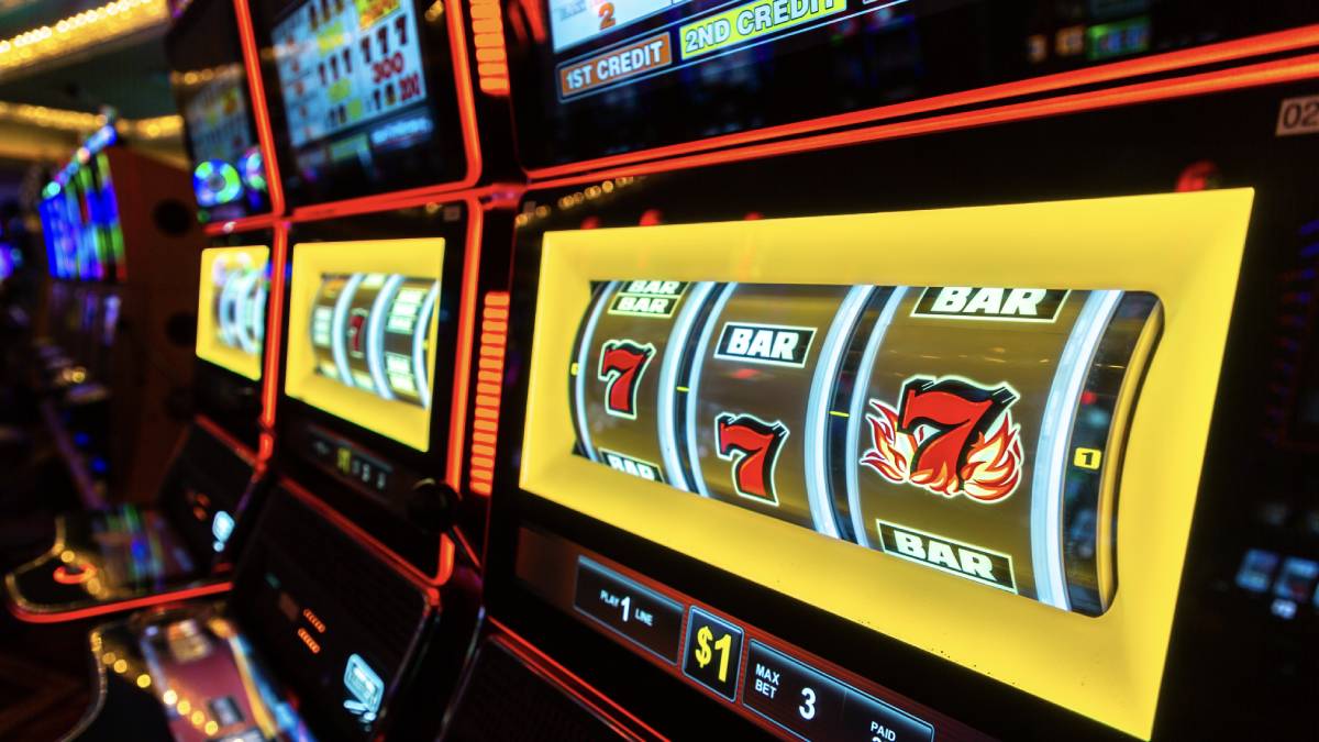 Close-up of a slot machine displaying three 7s, alongside a roulette wheel and craps dice, illustrating the number 7's prominent role as a lucky symbol in casino games.