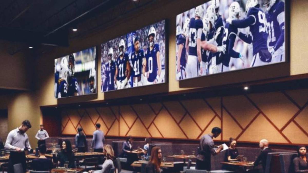 Modern restaurant at Happy Valley Casino with large flat-screen TVs mounted on the walls, displaying various sporting events. The dining area features comfortable seating and elegant decor, with patrons enjoying meals and drinks. The atmosphere is lively and inviting, catering to sports fans and diners alike.