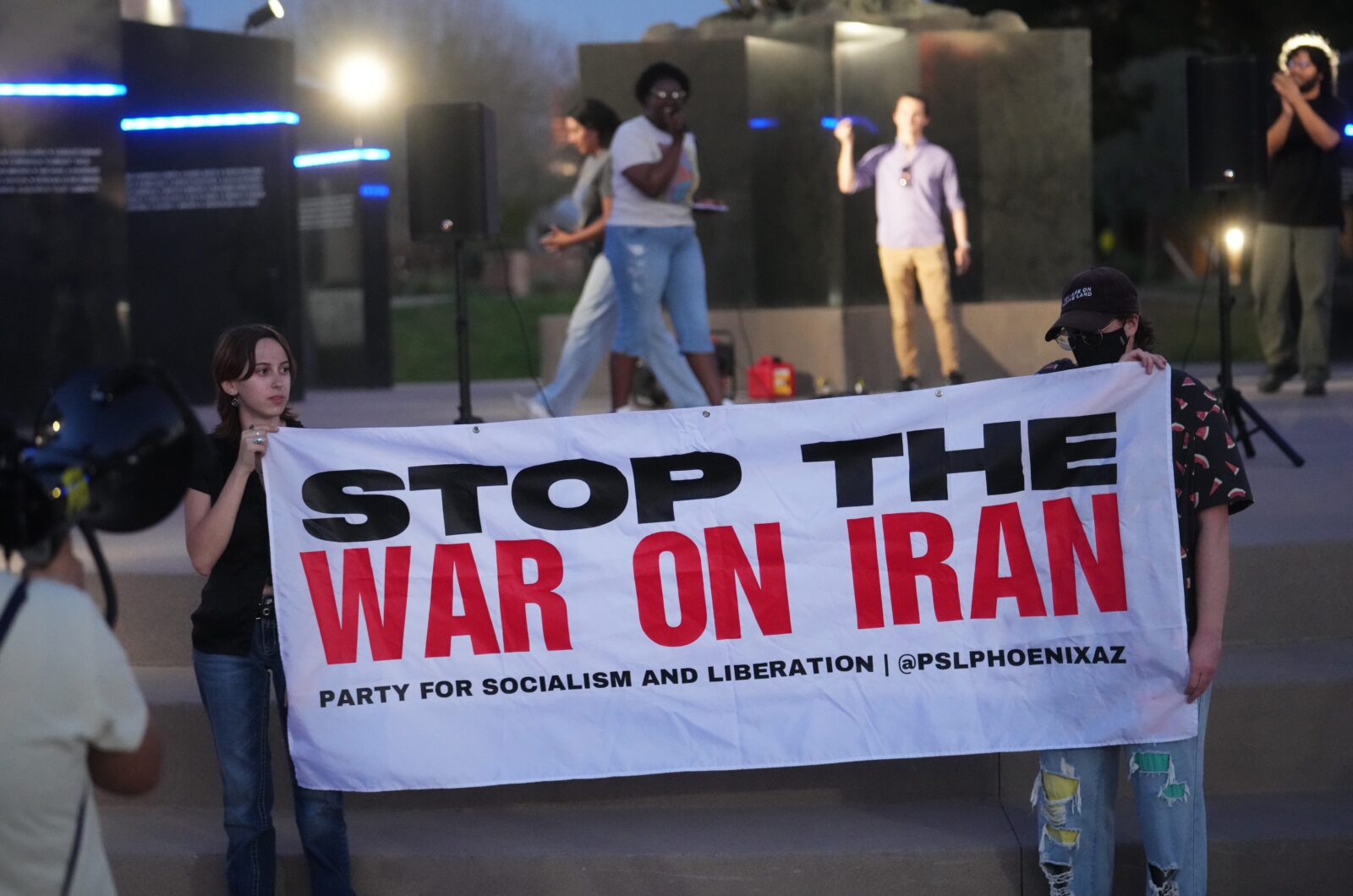 Protesters holding up a sign that says Stop The War On Iran.