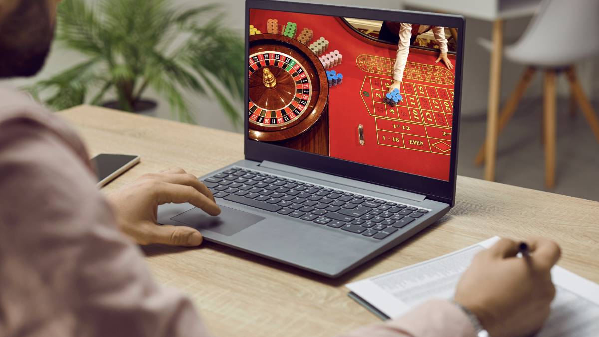 Young adult using a laptop to play online casino games at home
