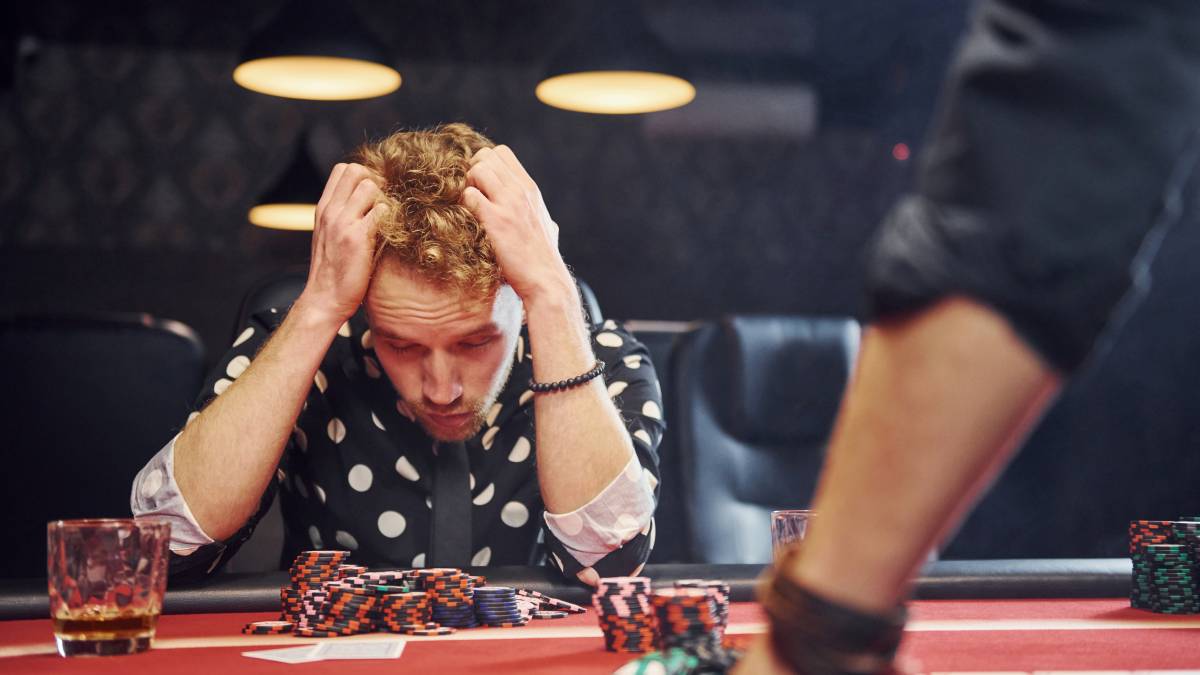 Casino player looking disappointed after losing money at a slot machine.