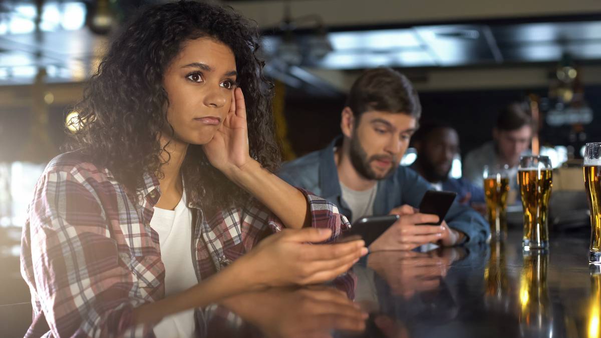 Woman looking disappointed after losing a sports bet on her phone.