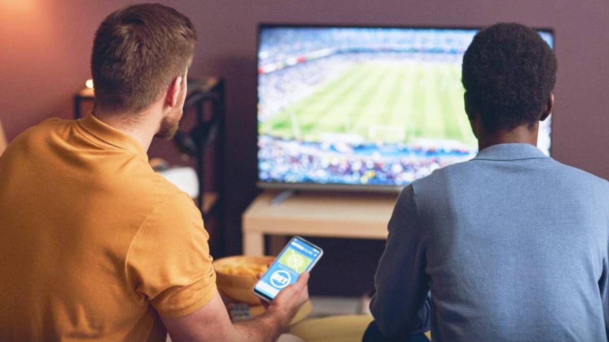 Gamblers use sports betting odds board and mobile prediction market app representing the legal fight over event contracts