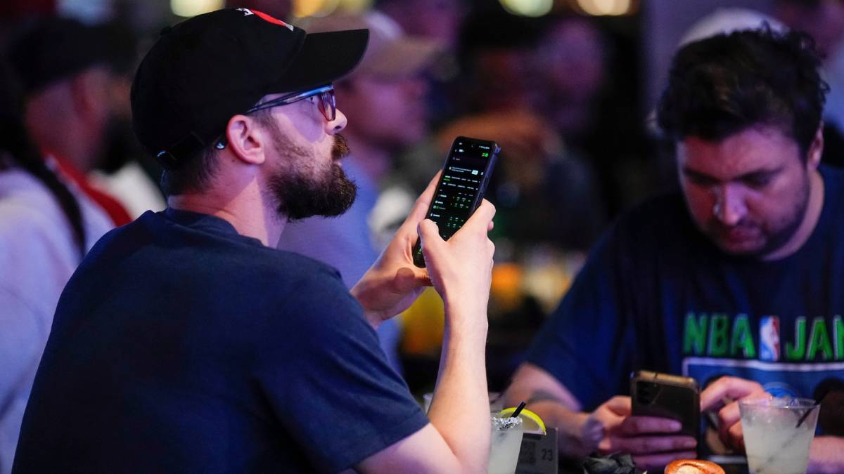Fan checking NFL betting odds on smartphone before kickoff, 2026 season