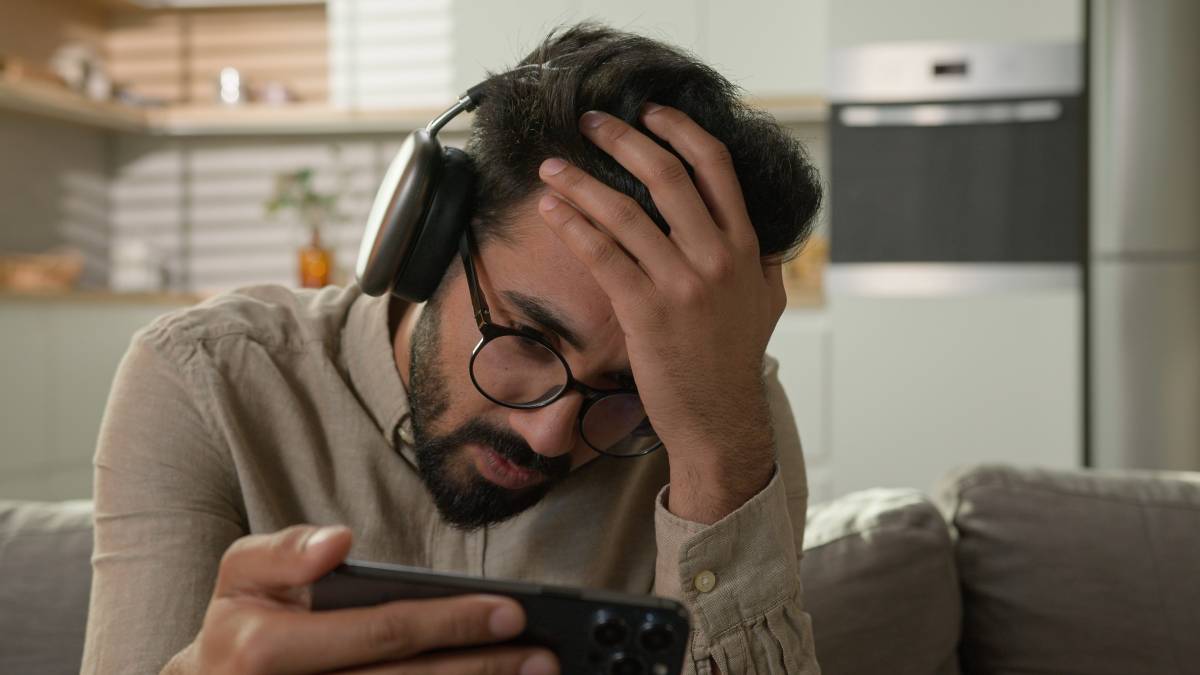 Young adult using mobile devices and computers to monitor betting odds during a game.
